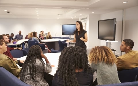Woman speaking in front of adults - Teach Plus
