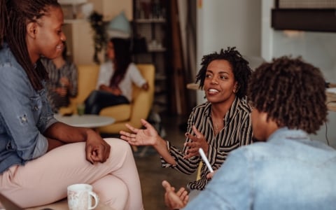 Three people in a discussion, coffee on table