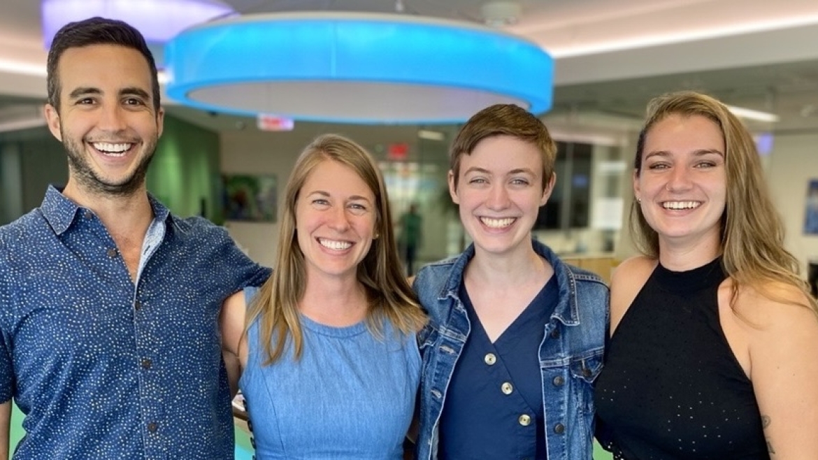 Four team members who ran the Schusterman Fellowship stand together in an office smiling.